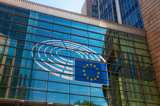 European Parliament logo and EU flag displayed on a modern glass building facade.