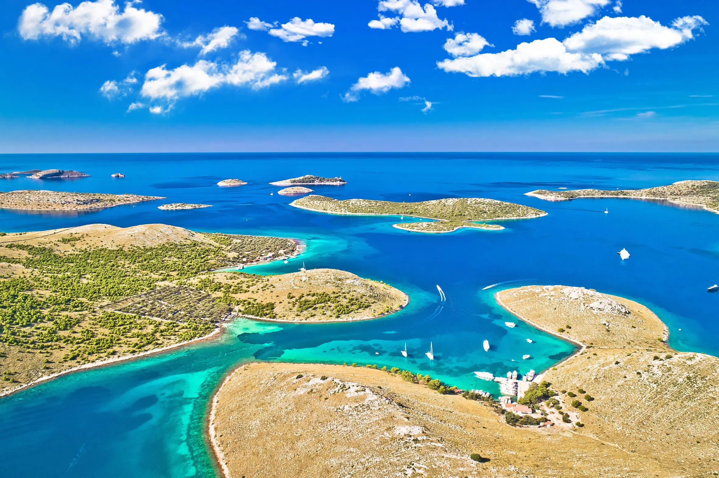 Aerial panoramic view of Kornati National Park in Croatia, showing an archipelago of islands, turquoise sea, and boats.