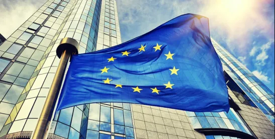 EU Flag shot from below in front of skyscraper; European Commission Proposes Cybersecurity Package Aimed at Reslilience