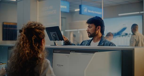 A traveler shows identification on a tablet to an airport security officer at a checkpoint counter.