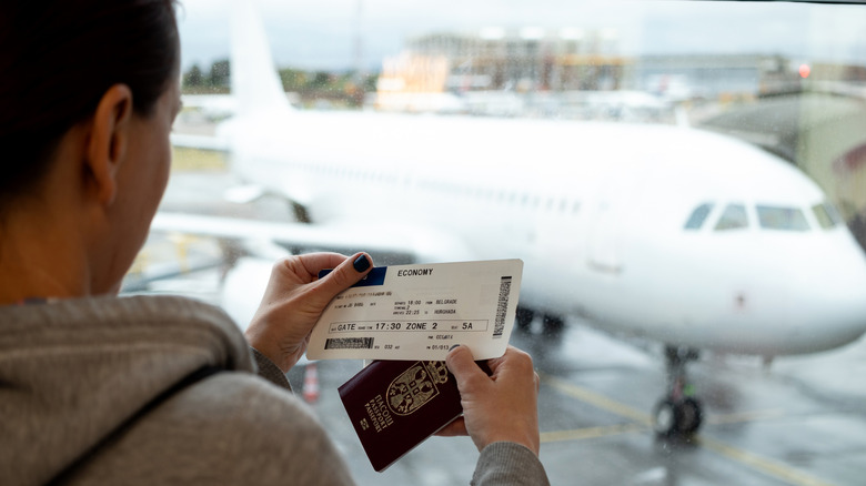 Passenger looking at an economy ticket in front of plane