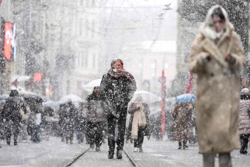 People walk with umbrellas on Istiklal Street during the snowfall in Taksim, Beyoglu district, Istanbul, Türkiye, Feb. 19, 2025. (AA Photo)
