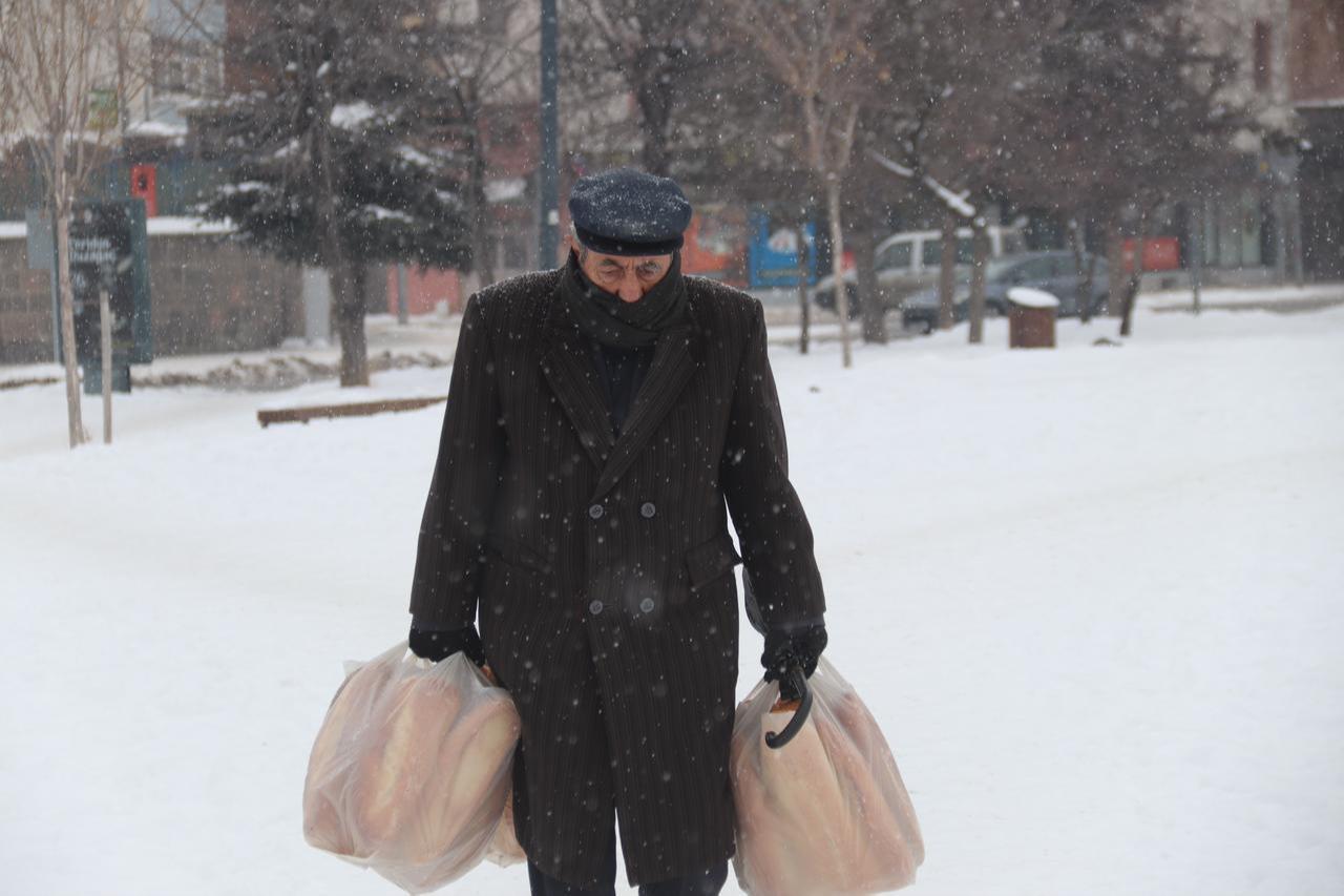 A resident struggles to carry grocery bags through falling snow as snowfall resumes in Kars, Türkiye, Jan. 23, 2026. (AA Photo)