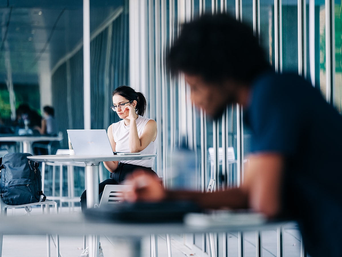 A UAB student and employee work on laptops outside East Science Hall