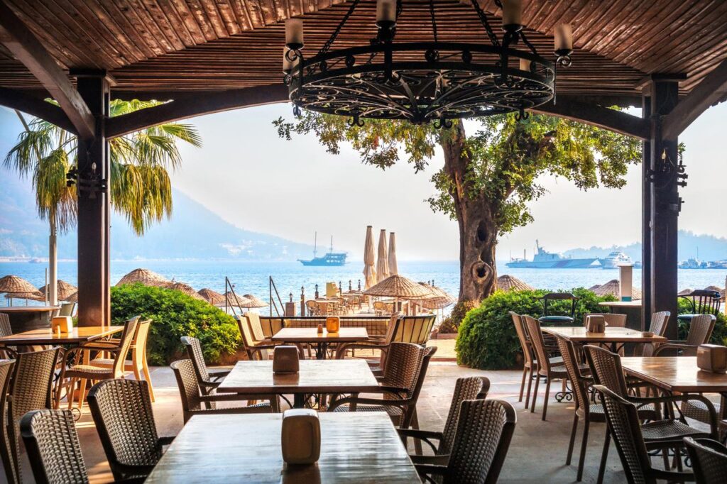 Cafe tables overlook the shoreline in Marmaris, Mugla, Türkiye. (Adobe Stock Photo)