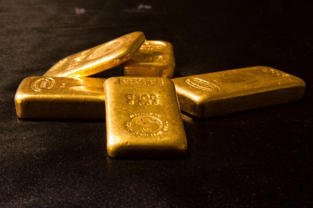 Gold bars displayed on a dark surface. (Adobe Stock Photo)