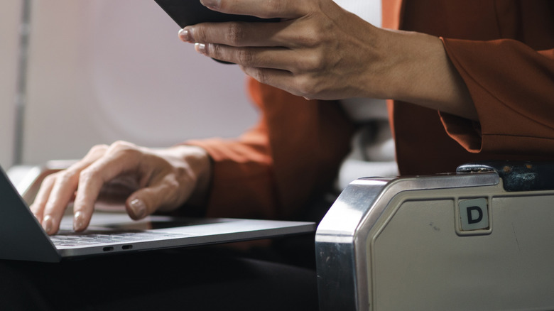 Closeup of hands working on laptop during a flight