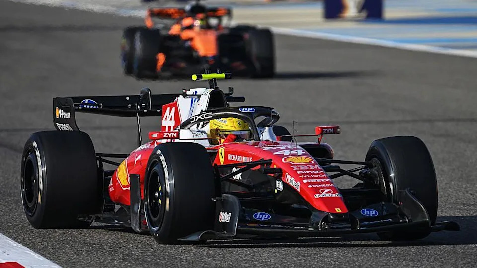 Lewis Hamilton drives the new Ferrari on track in Bahrain, with a McLaren in the background 