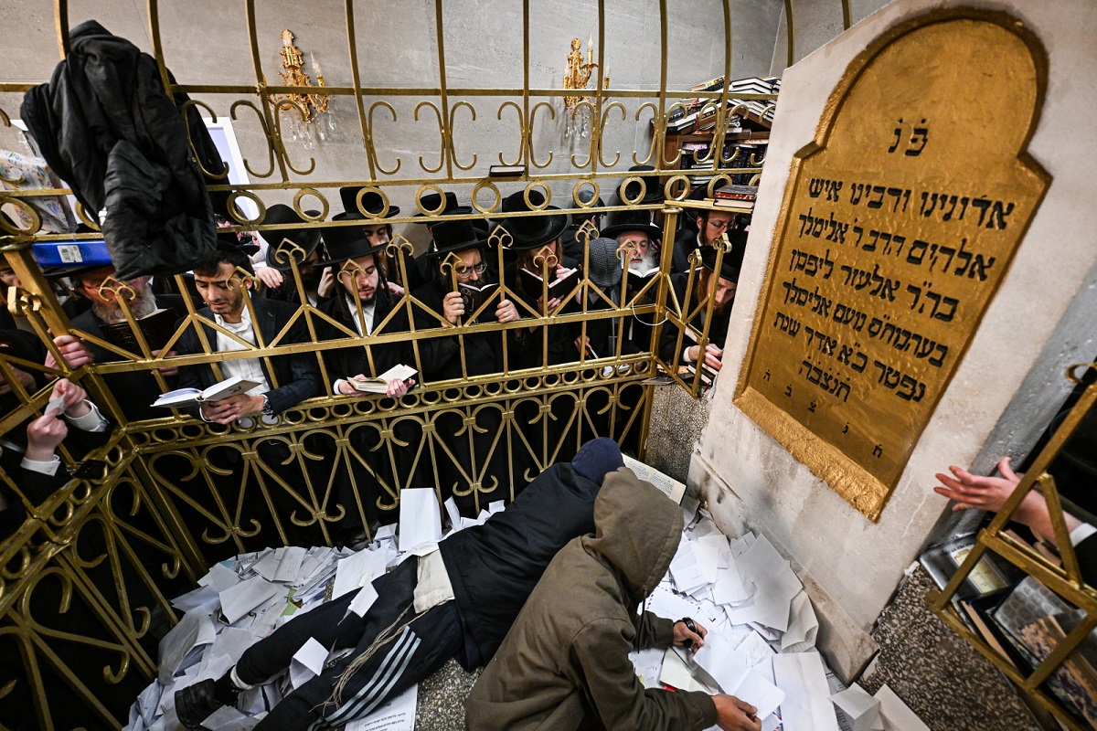 Pilgrims place handwritten prayers on small slips of paper at the rabbi’s tomb, seeking his intercession in personal matters.
