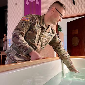 A soldier puts his hand in water.