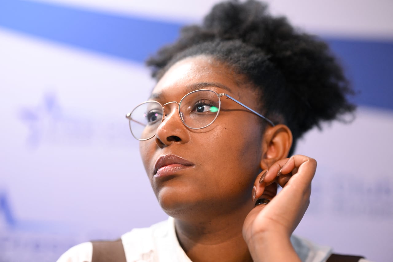 A woman in glasses looks to one side