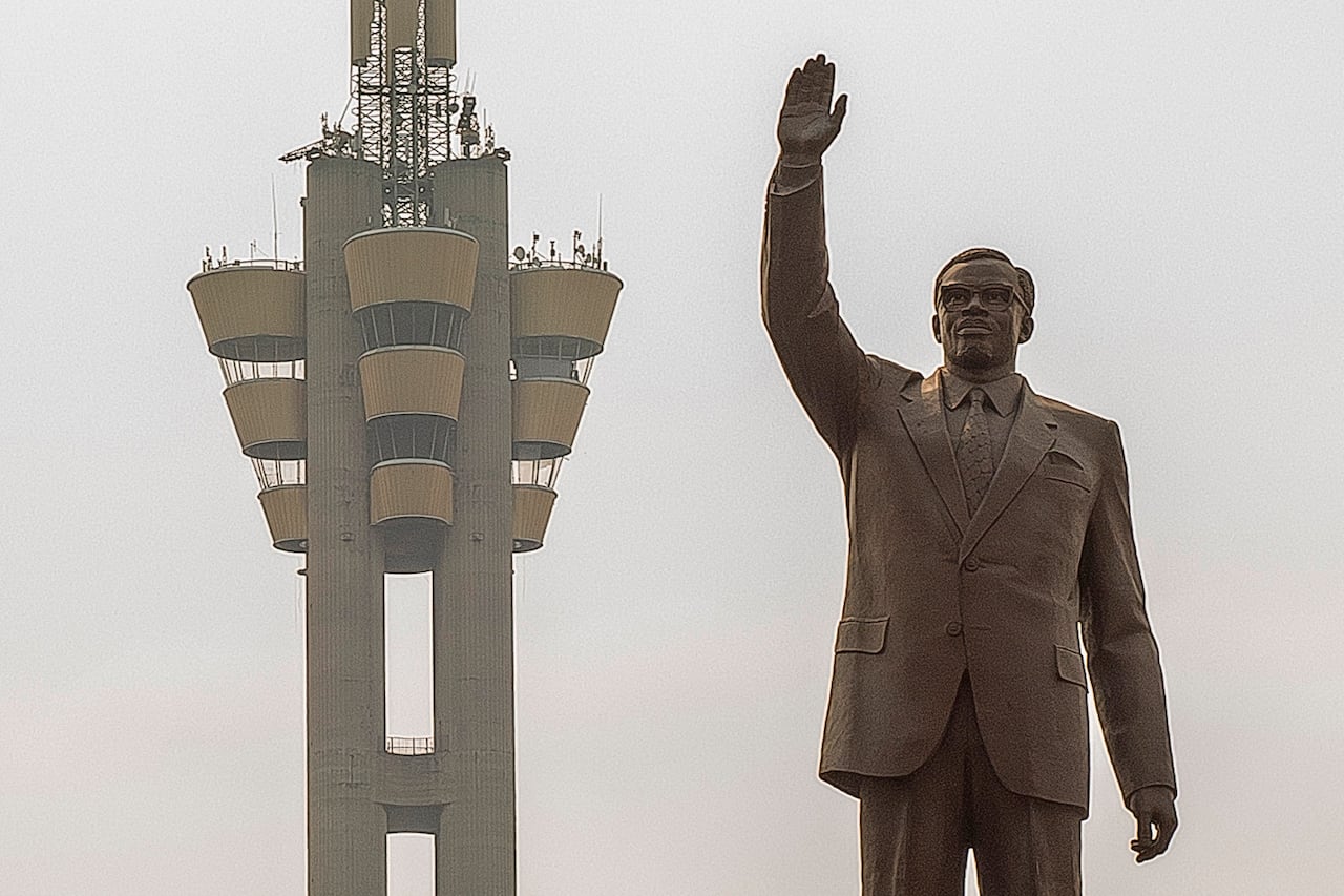 Statue of a man in a suit with glasses holding his hand in the air