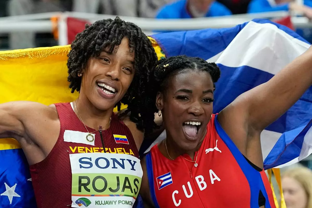 Gold medalist Leyanis Perez Hernandez, of Cuba, and silver medalist Yulimar Rojas, of Venezuela, pose after the women's triple jump final at the World Athletics Indoor Championships in Torun, Poland, Saturday, March 21, 2026. (AP Photo/Matthias Schrader)