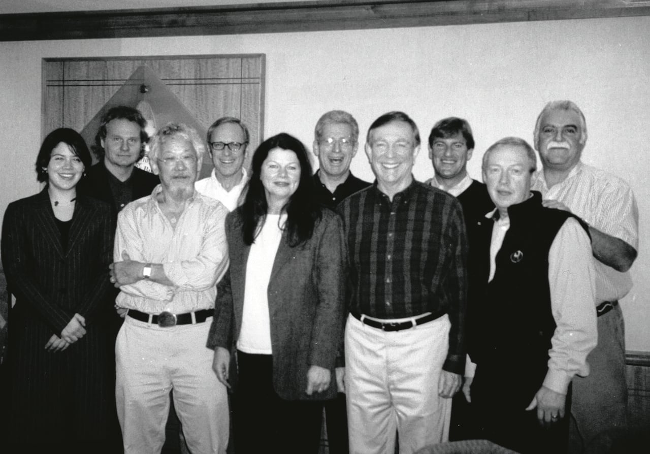 A group of women and men stand in a group photo together. 