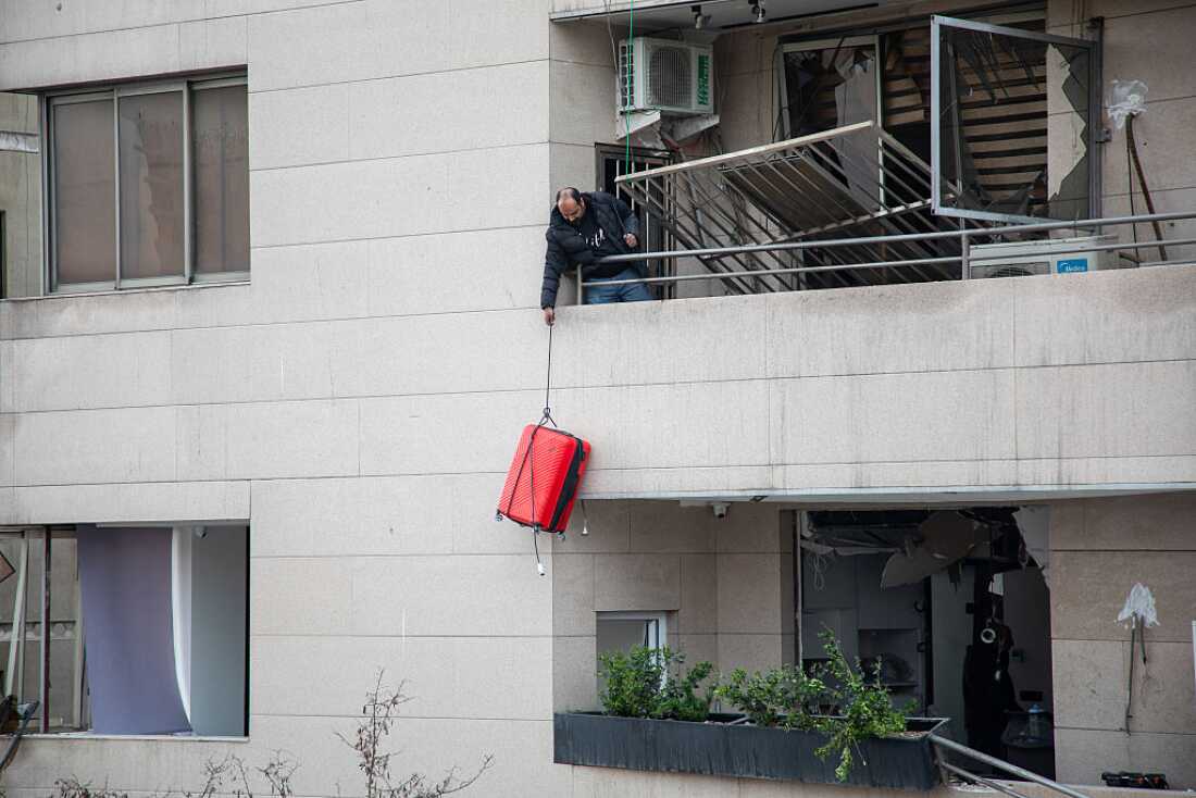 A man lowers a suitcase from the balcony of a building damaged by a strike in a commercial district of Tehran, Iran, during the U.S.-Israeli war on Iran, Sunday.