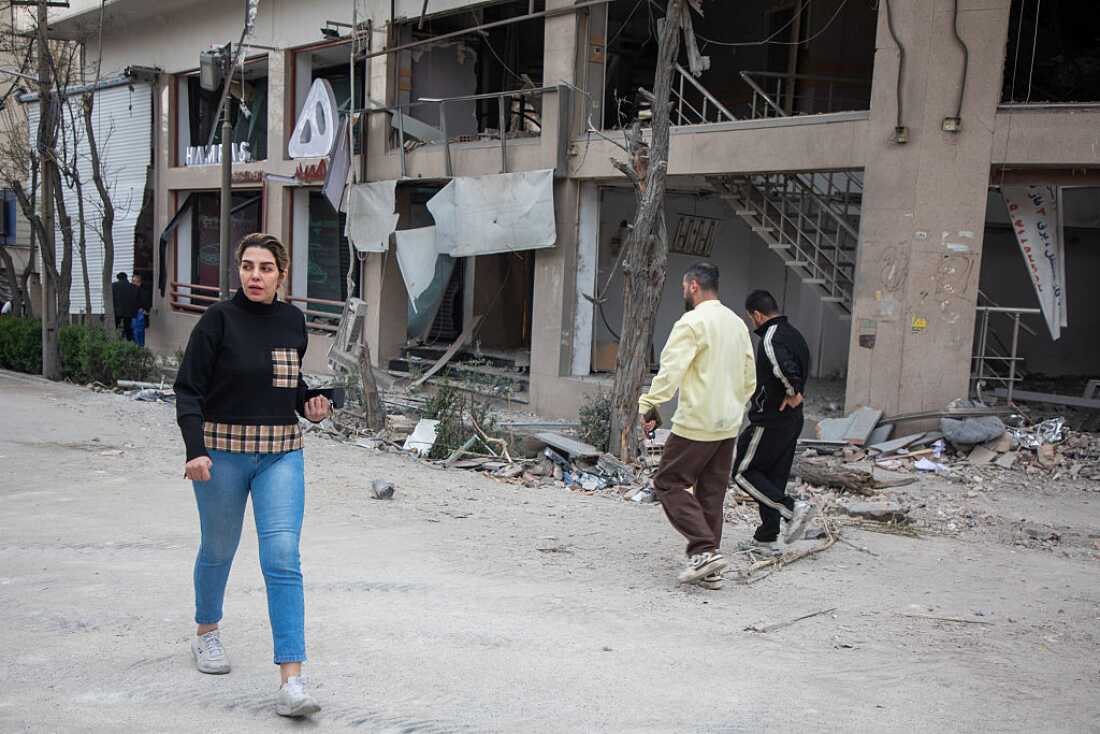 People pass near the site of a US-Israeli strike on a commercial district on March 29, 2026 in Tehran, Iran.