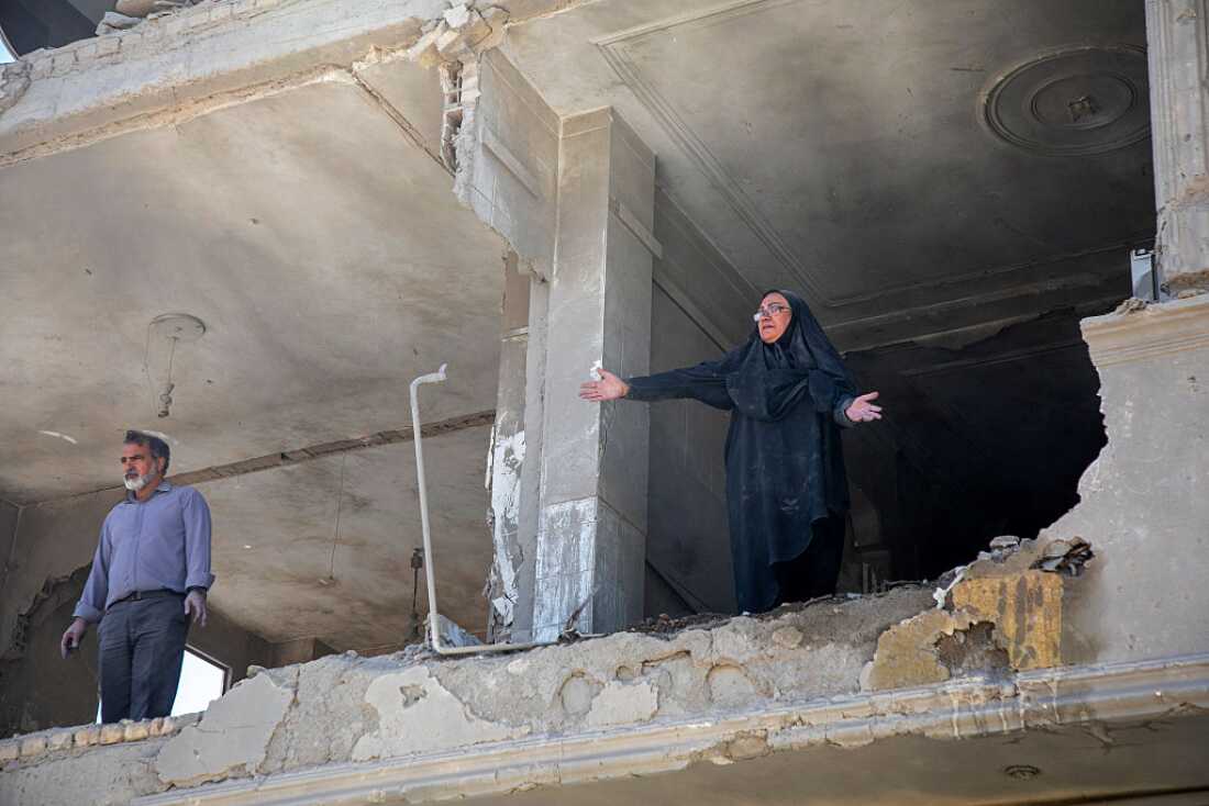 A resident gestures from an upper floor of a ruined residential building that was hit in an airstrike earlier this morning on March 30, 2026 in the west of Tehran, Iran.