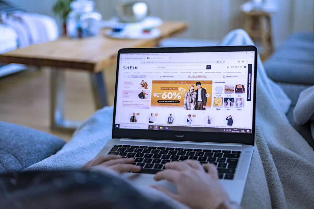 Sales: a person browses special offers during the sales period. A young woman lying on a sofa under a blanket looks at an online store on her laptop, e-commerce platform Shein, fast fashion
