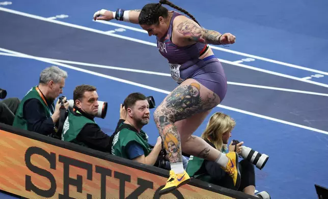 Chase Jackson, of the United States, jumps over a barrier celebrating after winning the gold medal in the women's shot put final at the World Athletics Indoor Championships in Torun, Poland, Friday, March 20, 2026. (AP Photo/Beata Zawrzel)