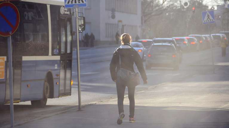 Photo shows a man walking on a dusty street.