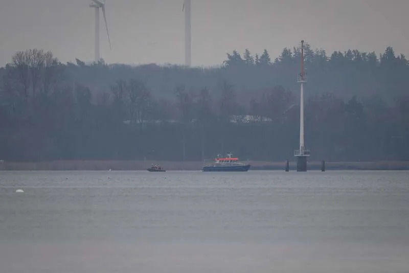 The "Uecker," a boat belonging to the water police, and a rubber dinghy are in Wismar Bay. A humpback whale stranded for days off Germany's Baltic coast has gotten stuck on another sandbank, a Greenpeace spokeswoman says. Philip Dulian/dpa