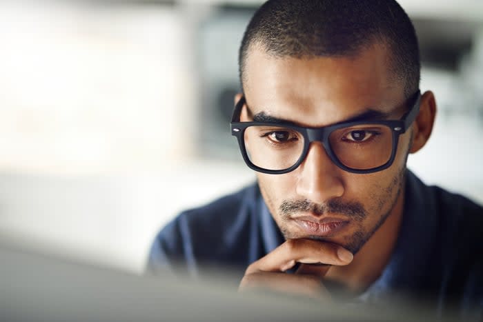 An investor considers a screen carefully while sitting at a desk.