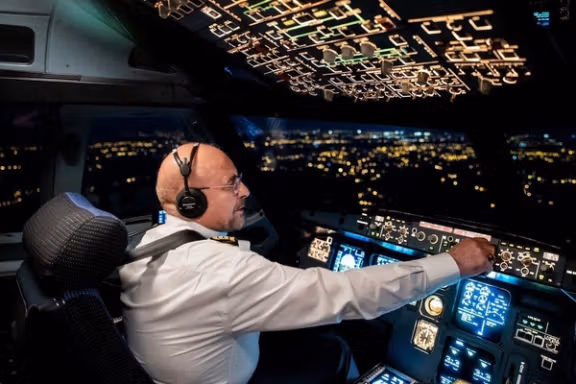Mohammad Bagher Ghalibaf sits in a pilot’s cockpit during a night-time flight, reflecting his background as a former IRGC air force commander.