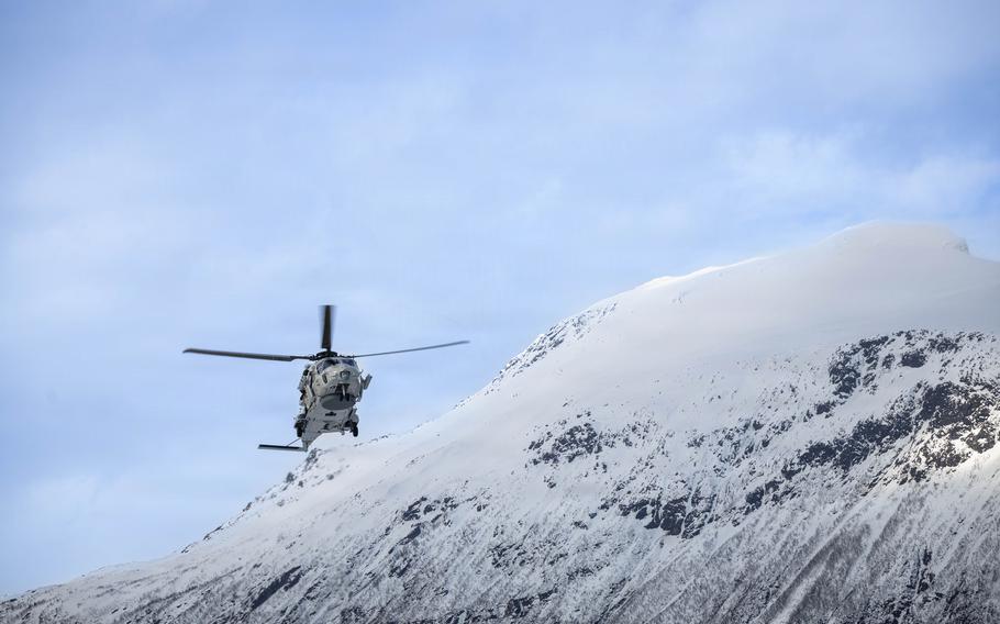 A helicopter flies just above a snowy mountain.