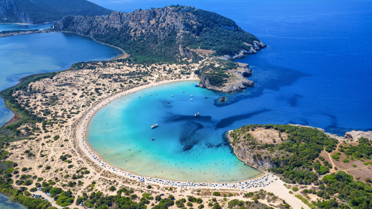 Filming Location for The Odyssey-Aerial view of the half circle shaped Voidokilia beach in Messinia, Peloponnese, Greece, with sand dunes and turquoise sea
