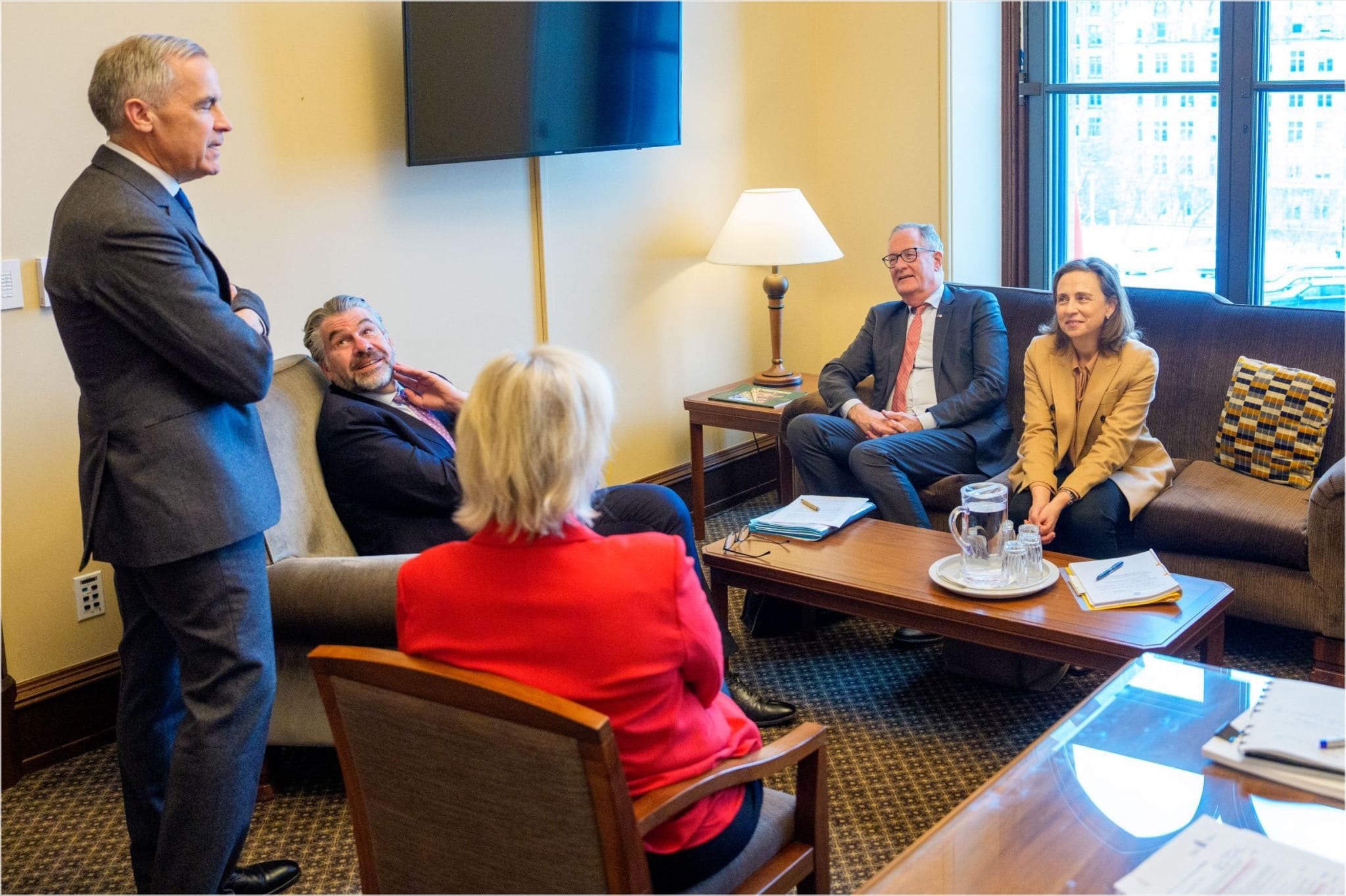 Five people wearing business attire, including Canadian Prime Minister Mark Carney, have a conversation.