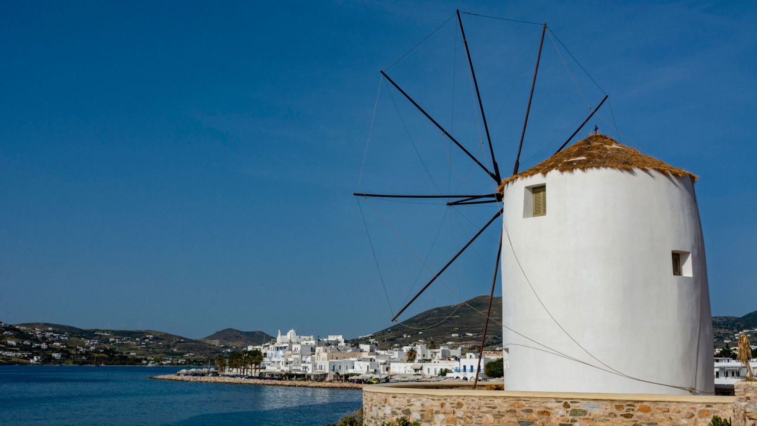 Filming Location for One Day-Parikia-A scenic view of the Parikia waterfront and a traditional windmill. Parikia, Paros Island, Cyclades Islands, Greece.