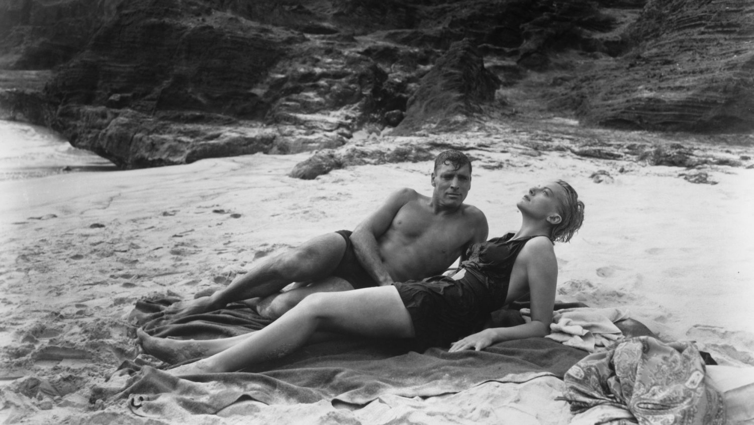 Burt Lancaster Bare-chested Burt Lancaster and Deborah Kerr wearing swimsuit relax on the beach in a scene from the 1953 film From here To Eternity