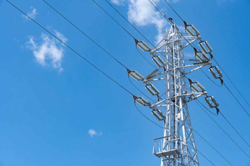 Power tower against blue sky with clouds