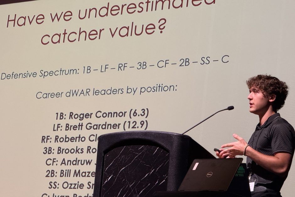 Zach Borowiak presents at a podium in front of a presentation screen