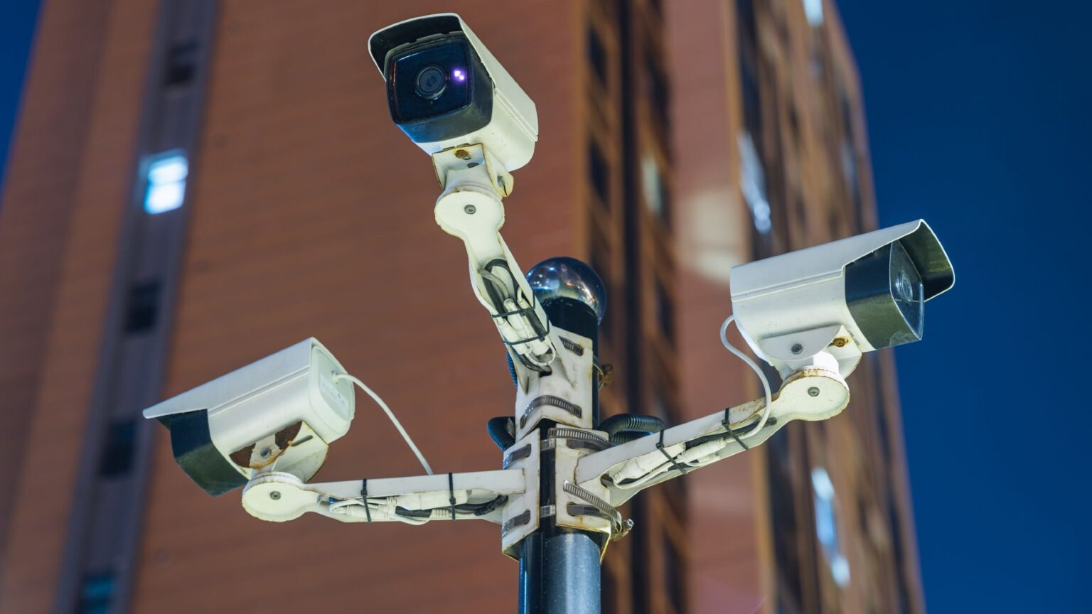 AI systems are enabling mass surveillance in the US, and there is no national law that ‘meaningfully limits’ the use of this data Four white security cameras are mounted in a cross-shape at the top of a street pole.