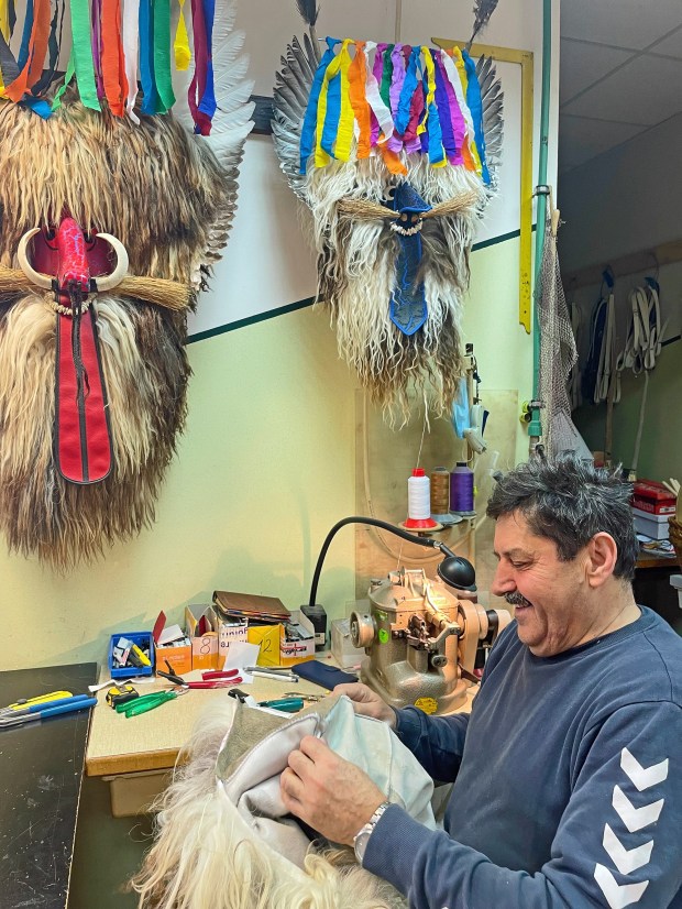 Kurent couturier Marko Klinc mends a sheepskin festival costume in his Spuhlja workshop. (Photo by Norma Meyer)