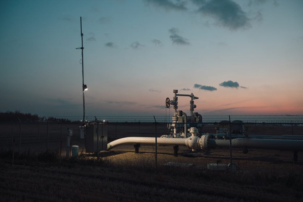 An oil and gas pipeline station is seen at twilight.