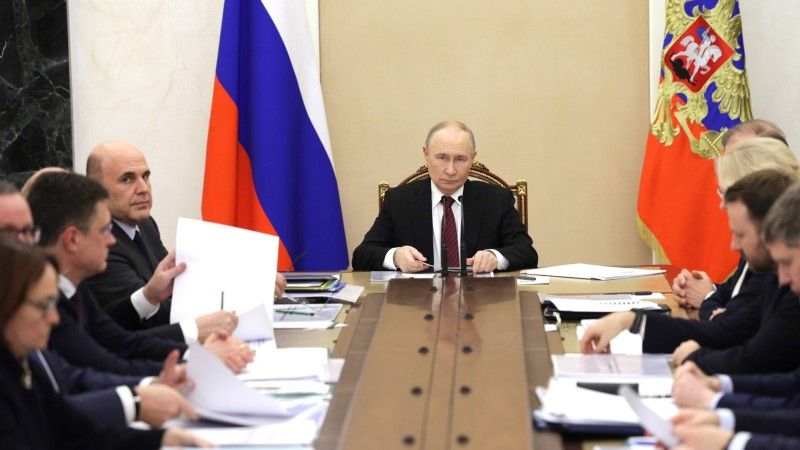 Władimir Putin siedzący przy długim stole na spotkaniu w sprawie gospodarki Rosji.