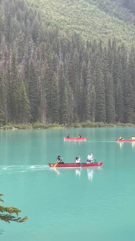 Red canoe gliding across the turquoise waters of Emerald Lake — Alberta, Canada