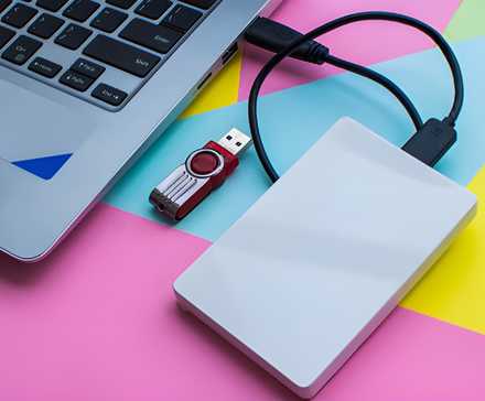 An external hard drive connected to a laptop next to a USB drive.