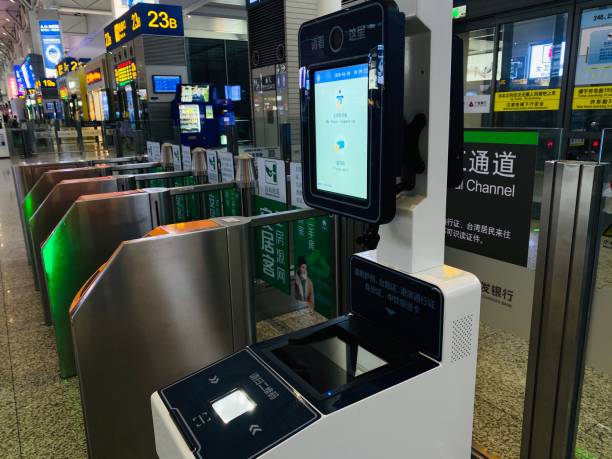 Automated border control gate with biometric scanner and digital screen in an airport terminal.