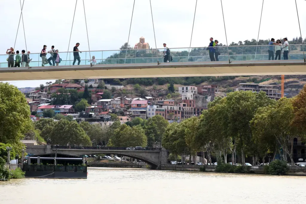 FILE PHOTO: People walk across the Bridge of Peace over the Mtkvari river in Tbilisi, Georgia September 10, 2025. REUTERS/Irakli Gedenidze/File Photo