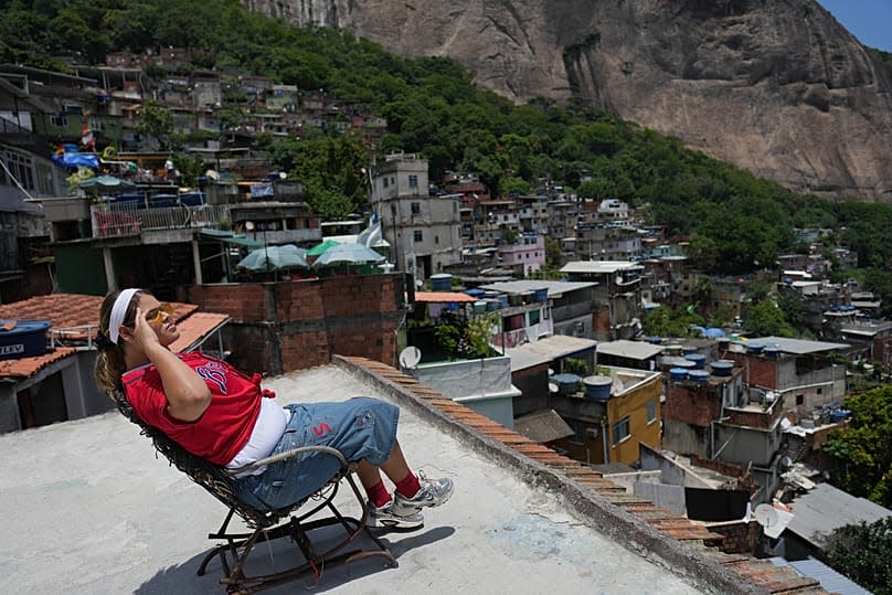 A tourist sits on a chair to be filmed by a drone in the Rocinha favela, at a time when Rio de Janeiro has seen a record number of international tourists.