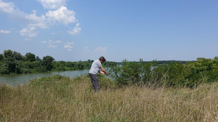 Man stood in a field by a river