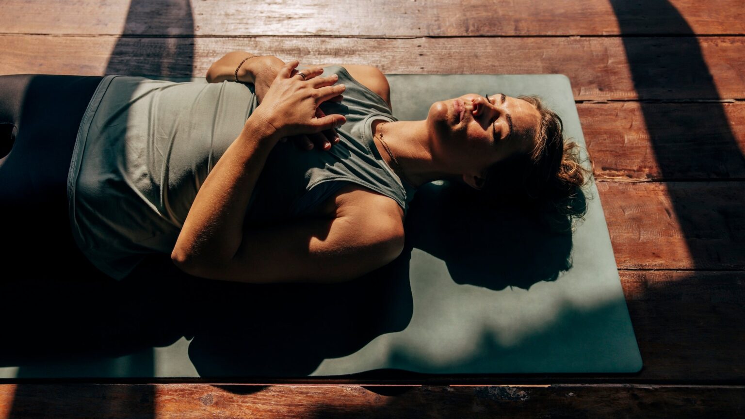 woman lies on yoga mat in the sun preparing for sleep, representing one of the top 2026 health and wellness trends