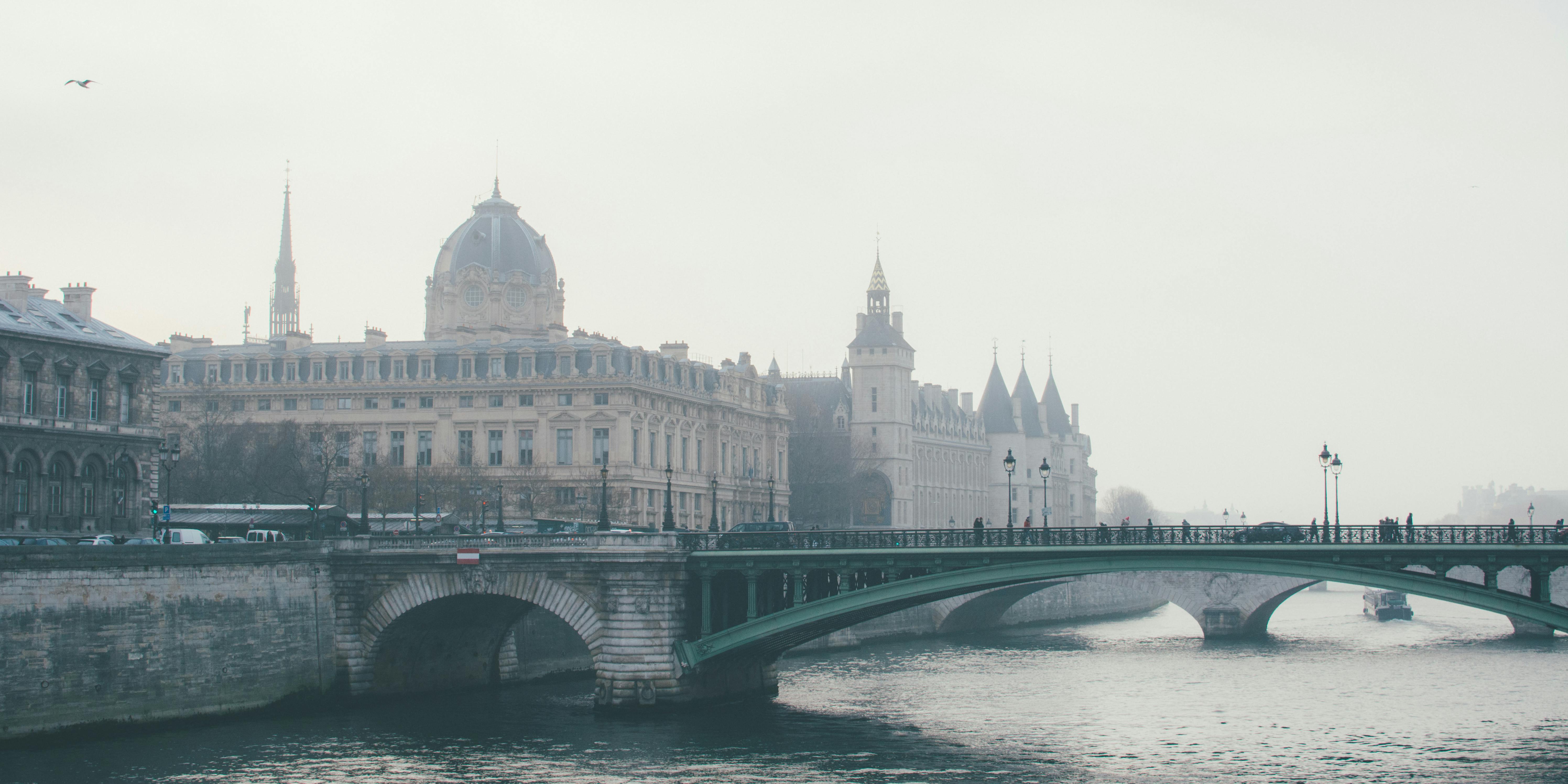 Historic buildings and Pont au Change bridge over the Seine River in Paris on a misty day.