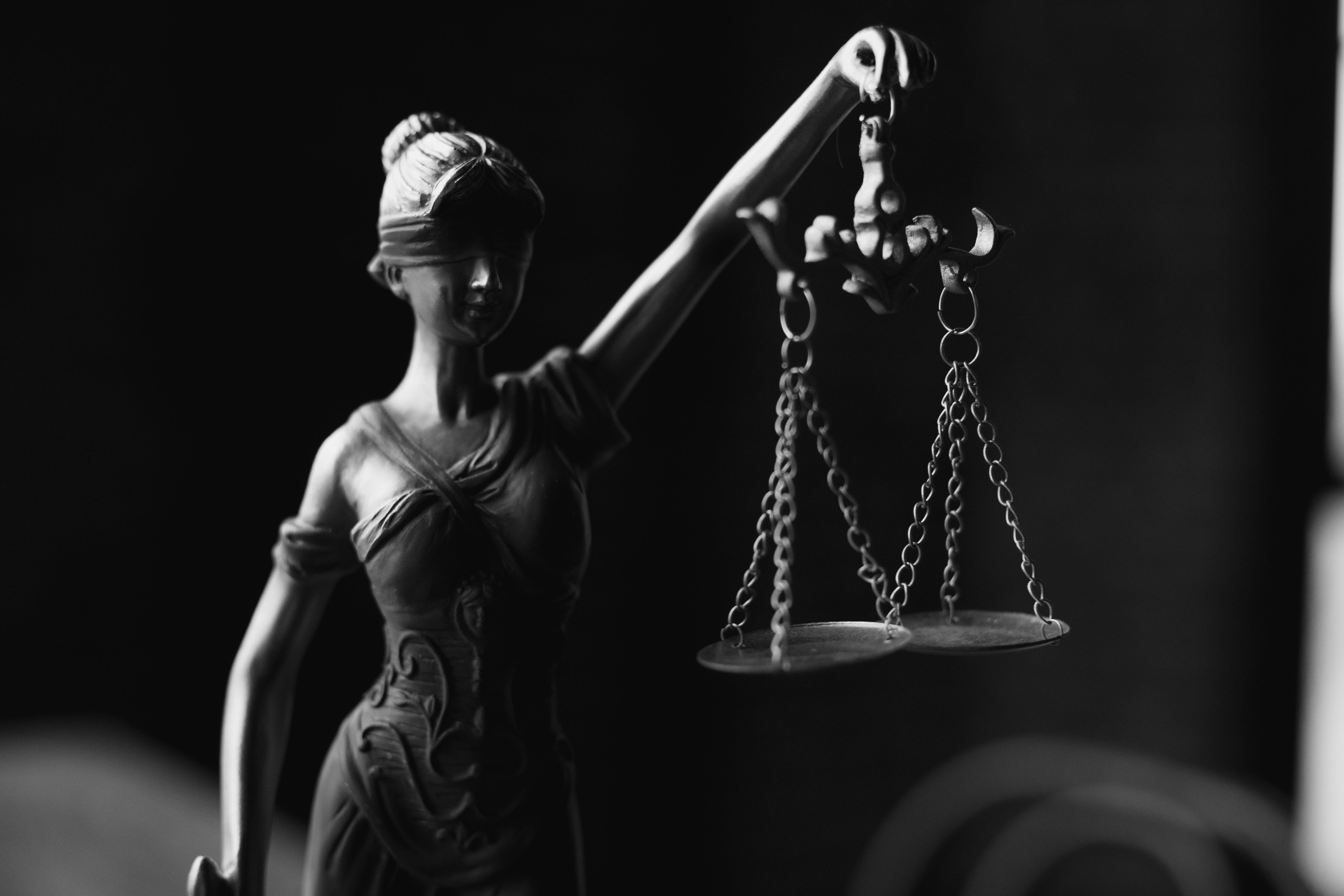 Black-and-white photo of the Lady Justice statue holding scales, symbolizing justice and impartiality.
