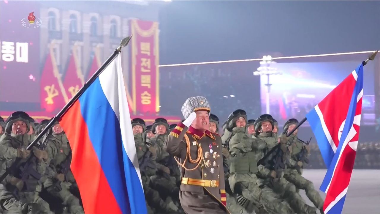 North Korean soldiers who fought in Ukraine fly the North Korean flag (right) and the Russian flag as they march during a military parade in Pyongyang on Feb. 26. (Yonhap)
