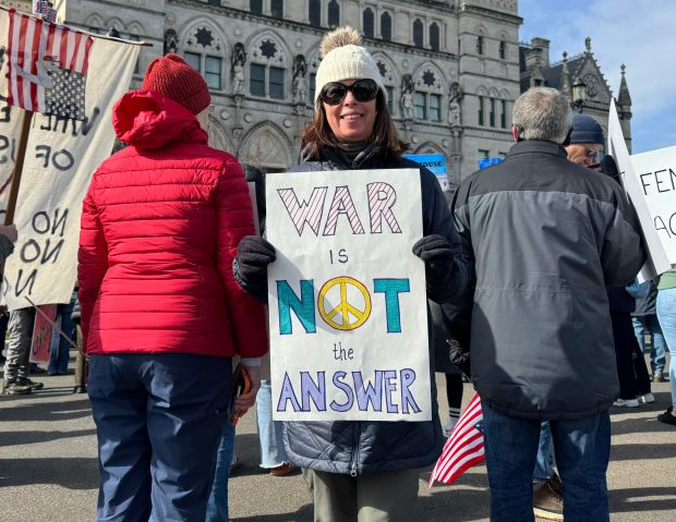 Kathleen Hindman of West Hartford holds an anti-war sign during the "No Kings" rally at the Connecticut State Capitol on Saturday, March, 28. Hindman, who has two sons in the U.S. Navy and a daughter-in-law in the U.S. Marines, said she is against the war in Iran. (Stephen Underwood/Hartford Courant)