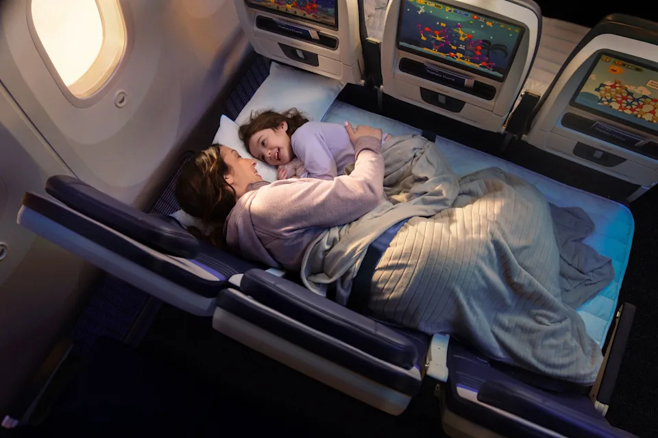 Mother and daughter relax on United's new lie-flat beds in economy class.